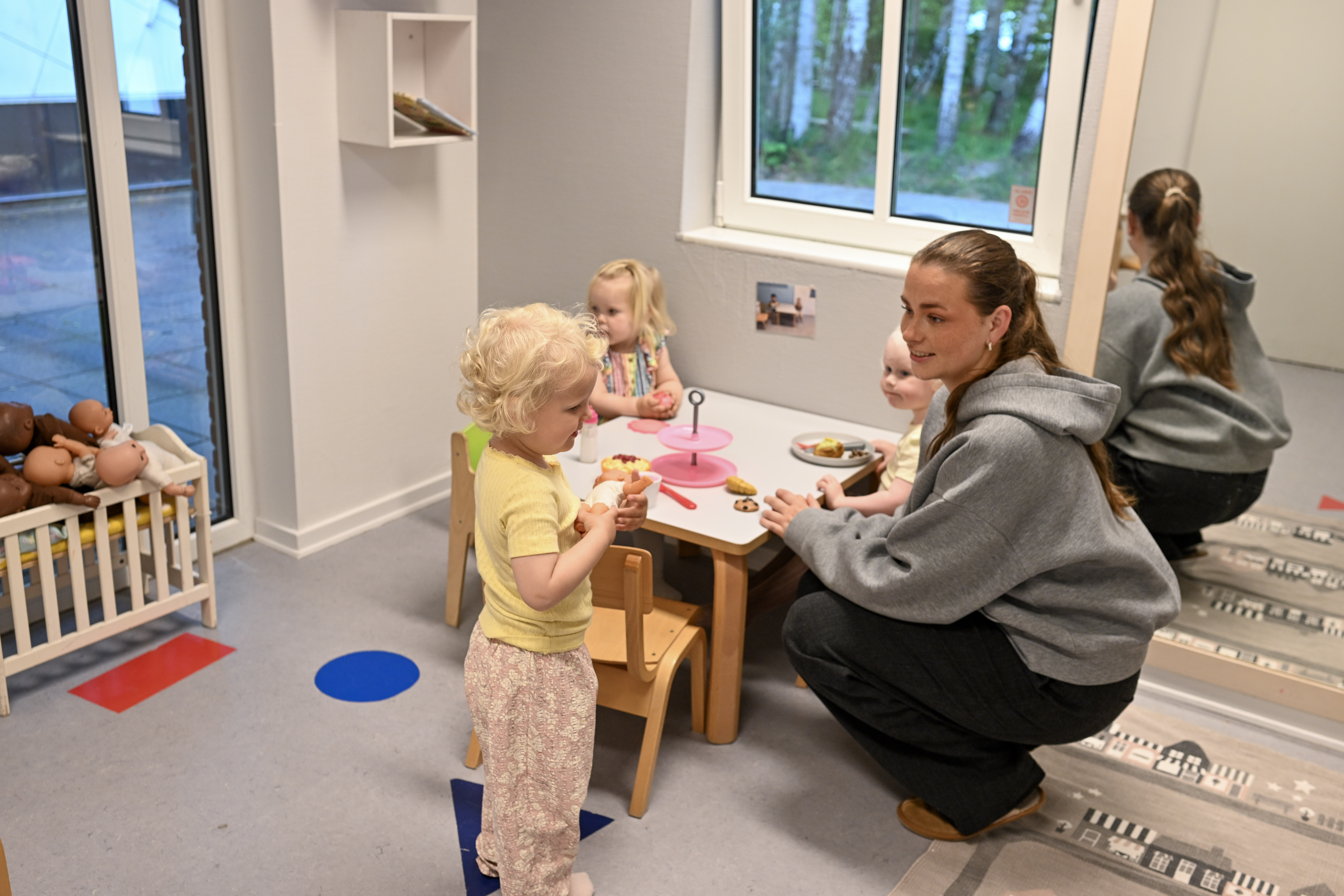 Voksen og tre børn leger ved bord