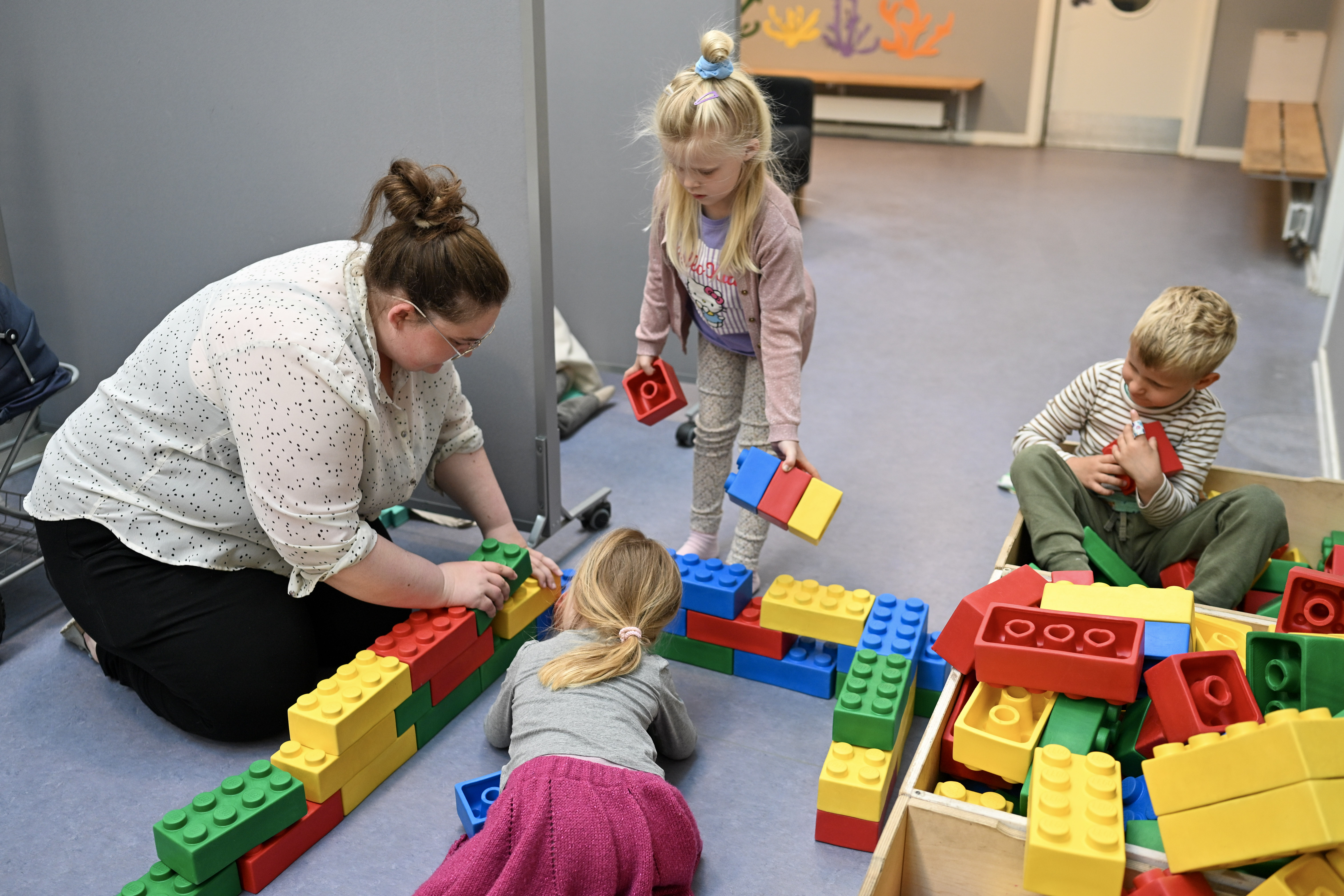 Voksen og tre børn bygger med store legoklodser