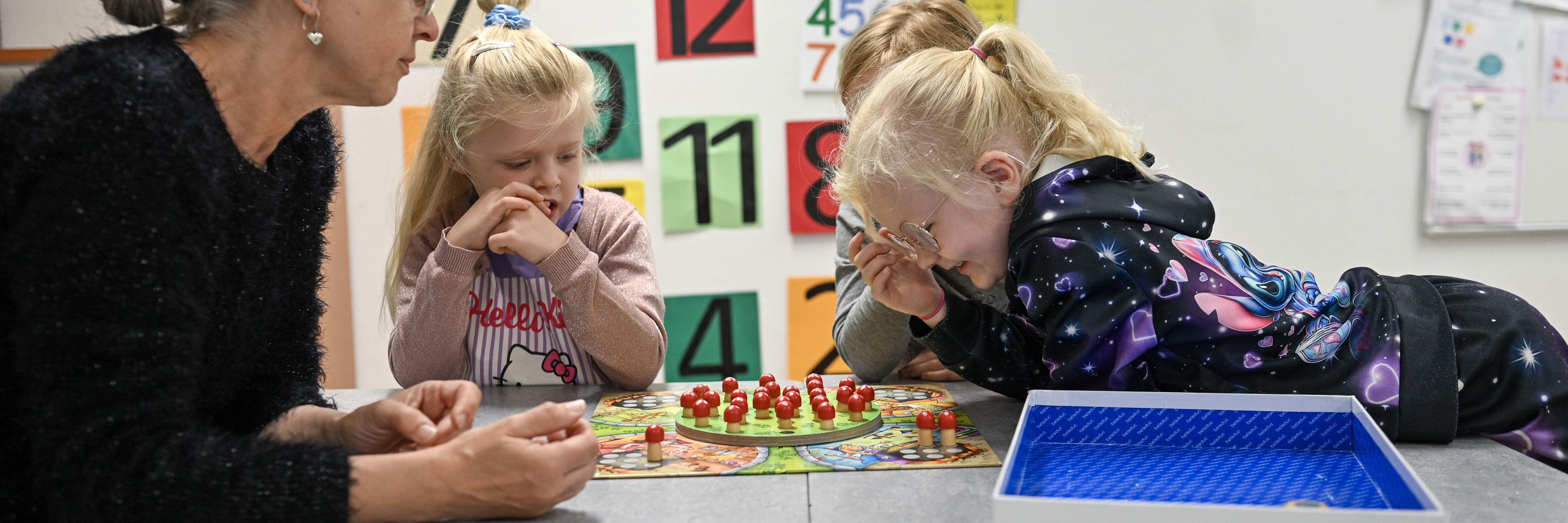 Voksen og tre piger spiller brætspil